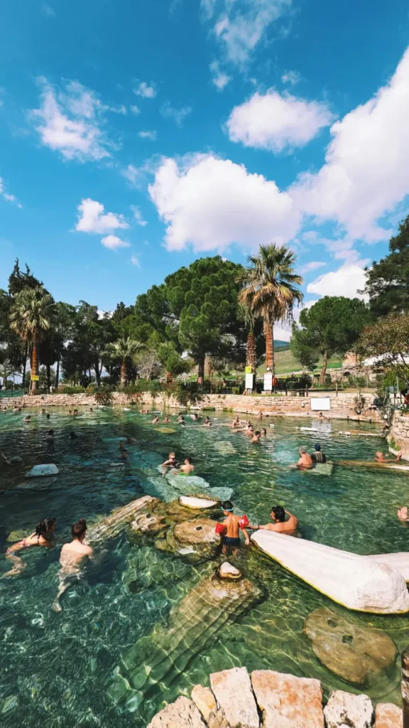 Visitors swimming in the Cleopatra Pool surrounded by ancient columns in Pamukkale, Turkey